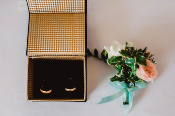 The composition of the open box with wedding rings and boutonniere.