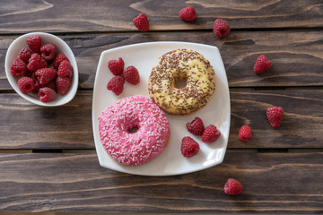 Ripe tasty raspberries and donuts on wooden background.Selective focus
