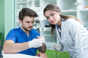 Fototapeta premium Dental prosthesis, dentures, prosthetics work. Prosthetics hands while working on the denture, false teeth, a study and a table with dental tools.