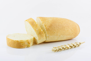 Sliced baguette and wheat ears on a white background