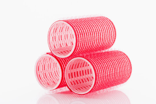 Red hair curlers on white background