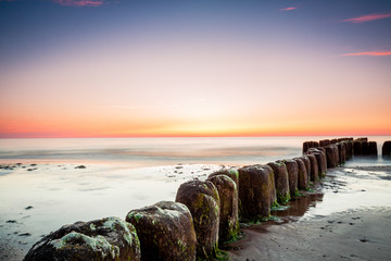 Sunset at Baltic sea, view on old breakwater piles.