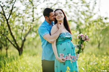 Naklejka premium Happy pregnant couple at turquoise dress on the garden