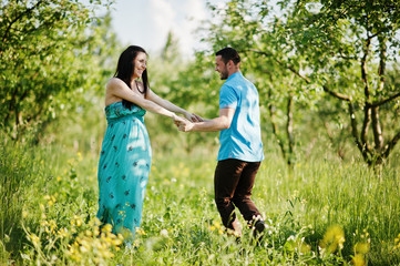 Happy pregnant couple at turquoise dress on the garden