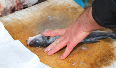 hands the fishmonger at the seafood market during cleaning of fr