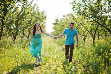 Fototapeta premium Happy pregnant couple at turquoise dress on the garden
