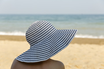 Fototapeta na wymiar woman head closeup in broad hat with sea beach background