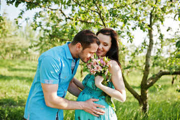 Fototapeta premium Happy pregnant couple at turquoise dress on the garden
