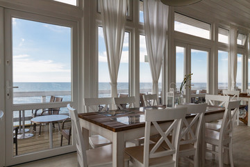 The interior of wooden cottage on the water with table and chairs.