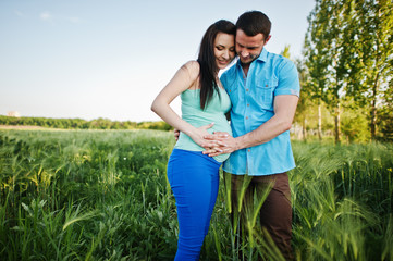 Happy pregnant couple on wreath field in love