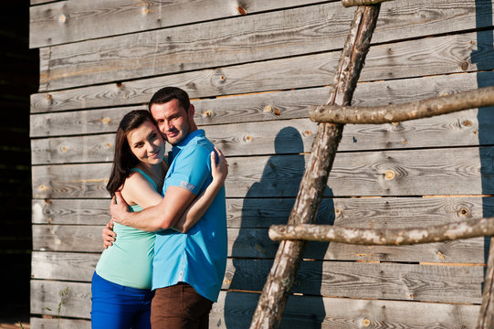 Happy pregnant couple background wooden barn at sunset