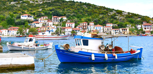 Traditional Greek fishing harbour with boats white houses by the