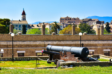 Old canons in the venetian fortress with the new Corfu Town in t