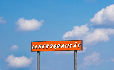 Lebensqualität - Schild vor blauen Himmel