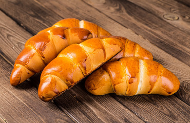 Tasty croissants with spikelets on grey wooden background