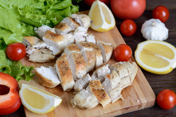 chicken fillet baked with rosemary on wooden board with vegetables