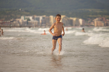 boy frolics in the sea with splashes and waves