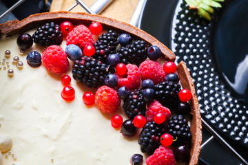 Cake with white chocolate mousse, lime confit, fruits and berries on top as decoration. The process of preparing a tea party with homemade fresh cake.