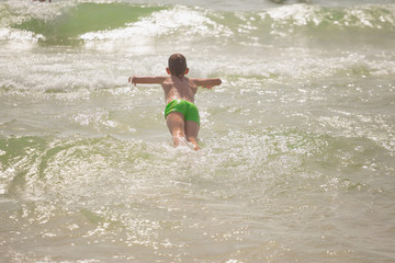 boy frolics in the sea with splashes and waves
