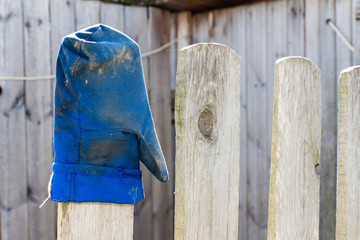 Blue mitten worn on the fence.