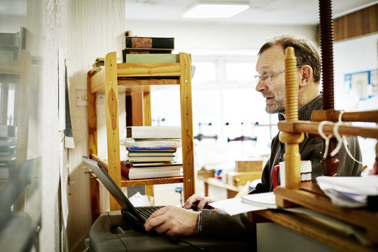 A man using a laptop computer on a bookbinding business. 