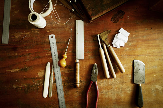 Overhead view of a workbench with hand tools for bookbinding. 
