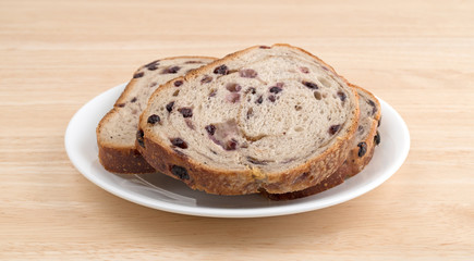Slices of blueberry streusel bread on white plate atop a wood table.