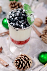 Delicious parfait dessert with bilberry, milk souffle and jello layers. Frozen treat in a glass on rustic wooden background