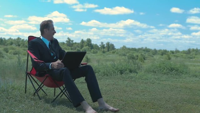 A businessman on laptop outdoors