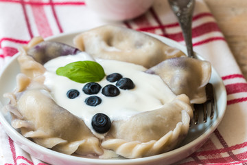 Vareniki. Dumplings with blueberries. Served with sour cream. Dish of Russian and Ukrainian cuisine. Selective focus
