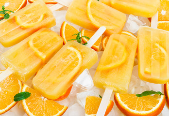 Fototapeta na wymiar Fruit orange ice lolly on ice cubes