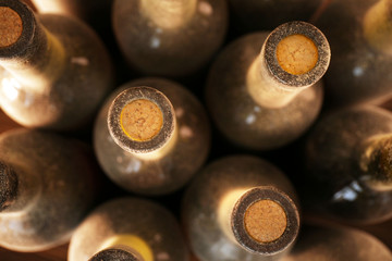 Stacks of dusty wine bottles on wooden background, upside view. Close up