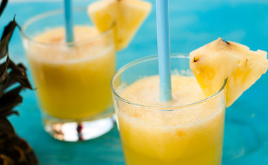 two glasses of fresh orange juice with blue straw on a blue background