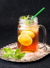 Ice tea with mint and lemon in a glass jar closeup