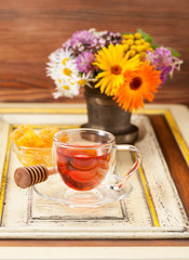 Herbal tea with honey and medicinal herbs in a mortar on a rustic background
