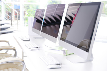 Modern computers on white wooden table in office