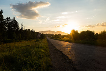 Fototapeta na wymiar Country road in the rays of the setting sun