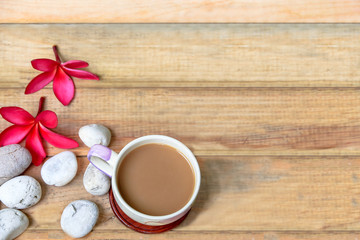 Fototapeta na wymiar coffee cup with Plumeria flower and stone on wood plate