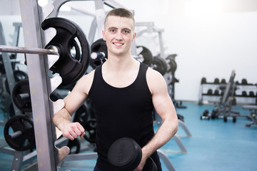 Fototapeta na wymiar Athletic man with a dumbells in gym