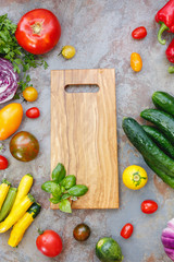 Assorted fresh whole vegetables and herbs around a chopping board. Preparing food concept