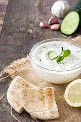 Tzatziki sauce in bowl on rustic wooden table

