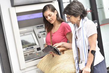 Home carer and disabled woman getting cash from bank