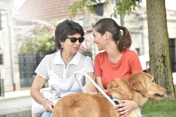 Blind woman and homecarer relaxing on bench