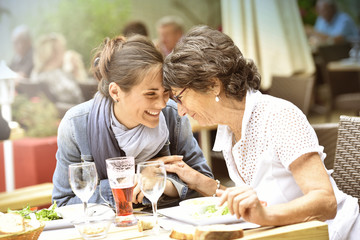 Senior woman with home carer having lunch at restaurant