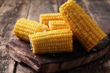 close view on Homemade golden corn cob with butter and salt on wooden table.