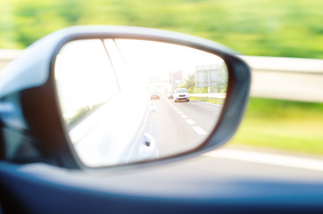 Concept of speed. Car driving on the road. Reflection in a car mirror.Rear view mirror reflection. Blurry background.