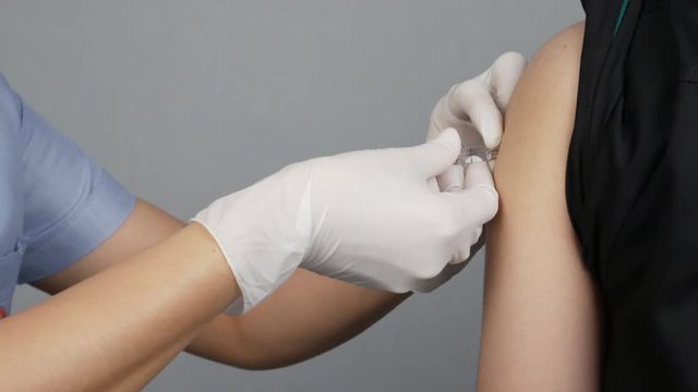 Doctor injecting flu vaccine to patient's arm in local hospital