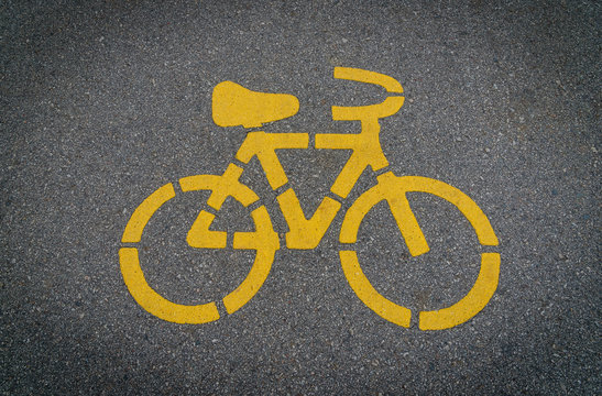 Yellow bycicle sign on lanes asphalt road.