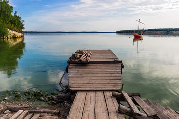 wooden boat on the river bank on forest background and blue sky