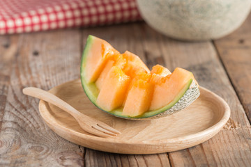 Fresh melon sliced on wood plate.